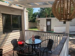 eine Terrasse mit Tisch und Stühlen auf einer Veranda in der Unterkunft Domki na Kwiatowej Okuninka - Orchówek in Orchówek + 60 Fotos