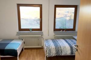 1 Schlafzimmer mit 2 Betten und 2 Fenstern in der Unterkunft Ferienwohnung mit fantastischem Ausblick & SmartTv in Waldstetten