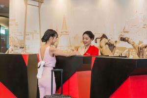 two women are standing at a desk in a museum at Vib Best Western Sanam Pao in Bangkok