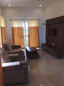 a living room with a couch and a tv at The Vihar service Apartment in Mysore