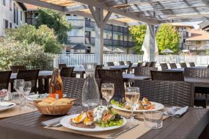 ein Tisch mit Tellern mit Essen und Gläsern Wein in der Unterkunft Village Vacances Le Junka in Vieux-Boucau-les-Bains