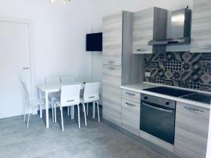 a kitchen with a dining table and white chairs at Le 5 Residence in Rodi Garganico