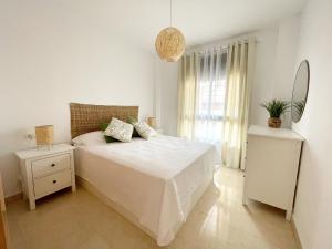 Habitación blanca con cama y ventana en El Arrecife - Apartamento a 2 minutos de la playa en El Puerto de Santamaría, en El Puerto de Santa María