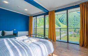 a blue bedroom with a bed and large windows at Hotel Darchi Kazbegi in Stepantsminda