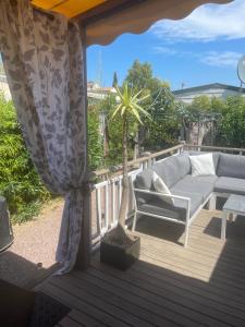a patio with a couch and a palm tree on a deck at Magic Mobile Montourey, 3 chambres, 2 salles de bain, piscine disponible sur place in Fréjus