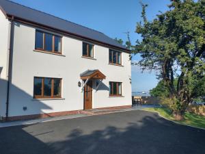 a white house with a basketball hoop on it at Martello View - 3 Bedroom Holiday Home - Llanreath in Pembroke Dock