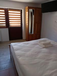 a bedroom with a white bed with a wooden door at Casa Tâmplarului 