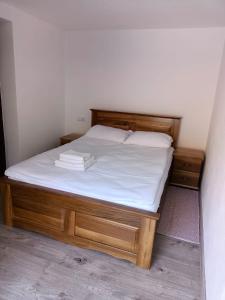 a bed with a wooden frame and white sheets at Casa Tâmplarului 