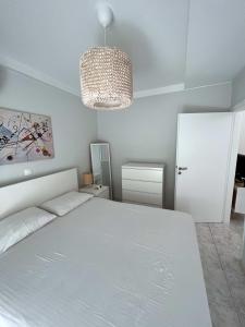 een slaapkamer met een wit bed en een kroonluchter bij Lovely apt near the beach in Athene