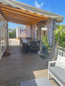 a patio with a table and chairs on a deck at Magic Mobile Montourey, 3 chambres, 2 salles de bain, piscine disponible sur place in Fréjus