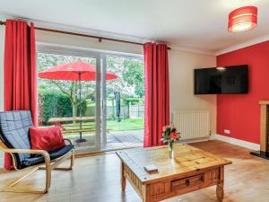 a living room with a table and a red wall at The Jays in Church Stretton