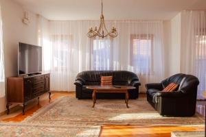 Una sala de estar con dos sofás de cuero y un televisor. en Engadin Apartments - Free Parking, en Sarajevo