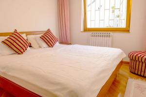 Un dormitorio con una cama blanca con almohadas y una ventana. en Engadin Apartments - Free Parking, en Sarajevo
