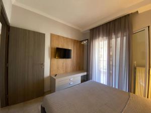 a bedroom with a bed and a dresser and a television at Hellen's Apartments in Ofrínion