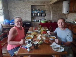 a man and woman sitting at a table with food at Guesthouse Lika in Ushguli