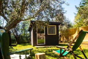 a tiny house in a yard with a green chair at Figueirinha Ecoturismo in Montes da Estrada