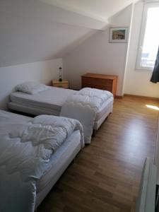 sypialnia z 3 łóżkami i drewnianą podłogą w obiekcie Aux Oyats d Isa w mieście Fort-Mahon-Plage
