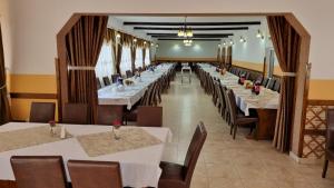 een lange eetkamer met witte tafels en stoelen bij Pensiune Restaurant Cosna in Coşna