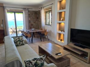 a living room with a couch and a television and a table at Leopolis Villas in Stoupa