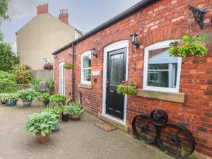 a brick house with a black door and potted plants at The Wheel House in Stalybridge