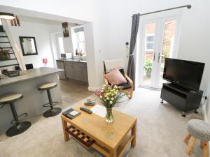 a living room with a television and a table with flowers at The Wheel House in Stalybridge