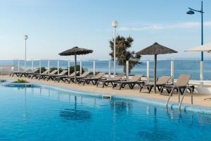 a row of chairs and umbrellas next to a swimming pool at AluaSun Far Menorca in S'Algar