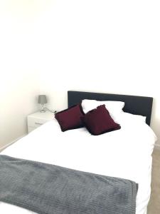 a white bed with two red pillows on it at Penthouse Apartment with seaviews in Walton-on-the-Naze