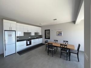 eine Küche mit einem Tisch und Stühlen sowie eine Küche mit weißen Schränken in der Unterkunft Villa Janja in Komarna