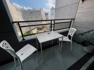 einen Balkon mit einem Tisch, 2 Stühlen und einem Fenster in der Unterkunft Donggang Homestay-Dongfan in Donggang