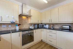 una cocina con armarios blancos y encimeras negras en Hullidays East Modern Detached 3 Bed House en Hull