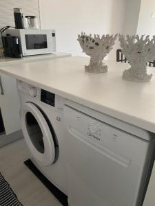 una lavadora blanca bajo una encimera en la cocina en Balaia I en Olhos de Água