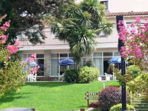 a garden with pink flowers and blue umbrellas at Hotel Rideamus in Villa Gesell