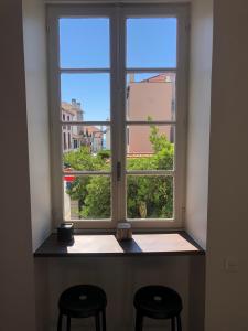 een raam met twee krukken ervoor bij Bel appartement, offrant calme et luminosité, proche Côte des Basques in Biarritz