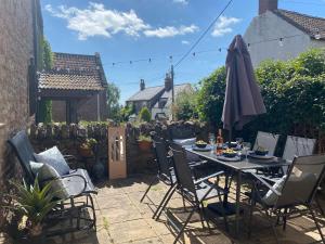 a table and chairs with an umbrella on a patio at The Nook- A Rustic Cottage in a Beautiful Village. in Draycott