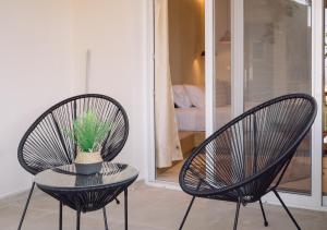 two chairs and a table with a potted plant at Eleftherias Suites - Near Beach Apartments in Marathi