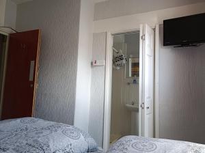 - une chambre avec un lit et une télévision murale dans l'établissement Stafford House, à Blackpool