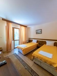 um quarto de hotel com duas camas e uma janela em Почивна база "Боженишки Урвич" em Bozhenitsa