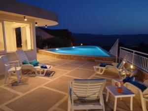 eine Terrasse mit Stühlen und ein Pool in der Nacht in der Unterkunft Villa Franka with swimming pool in Bol + 142 Fotos