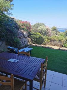 Une table et des chaises en bois sont disponibles sur la terrasse. dans l'établissement Résidence pinedda, à Propriano