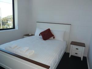 a bedroom with a white bed with two towels on it at Bellevue on Bentley - Unit 2 in Bridport