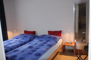 Una cama con edredón azul y almohadas rojas en un dormitorio en Zermatt La Vallée en Zermatt