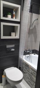 a bathroom with a white toilet and a bath tub at Apartament Kaja in Siemianowice Śląskie