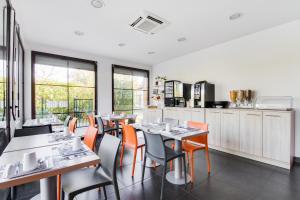 een eetkamer met tafels en oranje stoelen bij All Suites Le Teich – Bassin d’Arcachon in Le Teich