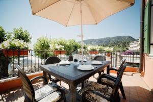 a table with chairs and an umbrella on a balcony at Welcome Traveller LA CASA DEGLI ACQUERELLI in Garda