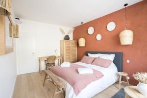 una camera da letto con un grande letto con lenzuola rosa di Les pénates bordelaises - Maison d'hôtes - Guesthouse a Bordeaux