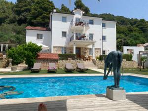 a statue next to a swimming pool in front of a house at Villa Joy 4ever in Banjol