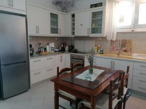 加拉塔斯Trizinia View的厨房配有白色橱柜、桌子和冰箱。