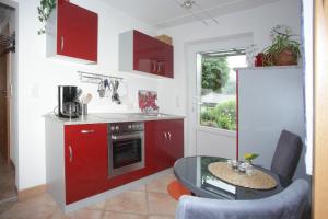 a kitchen with red cabinets and a small table and a kitchen with a refrigerator at Ferienwohnung Schwarzwaldblick in Bühlertal