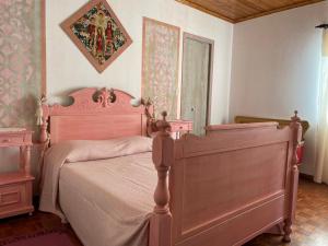 a bedroom with a pink bed and a mirror at Avó da Rosa in Ribeira Quente