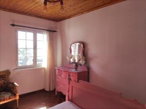a bedroom with a red dresser and a window at Avó da Rosa in Ribeira Quente